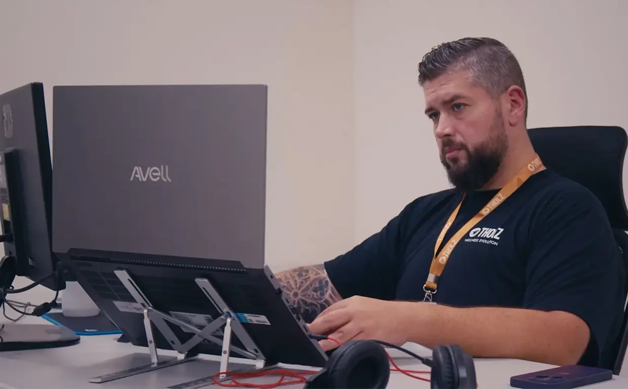 Colaborador da Assistência Técnica da Tholz trabalhando em notebook no escritório, com foco em atividades técnicas e análise de sistemas.